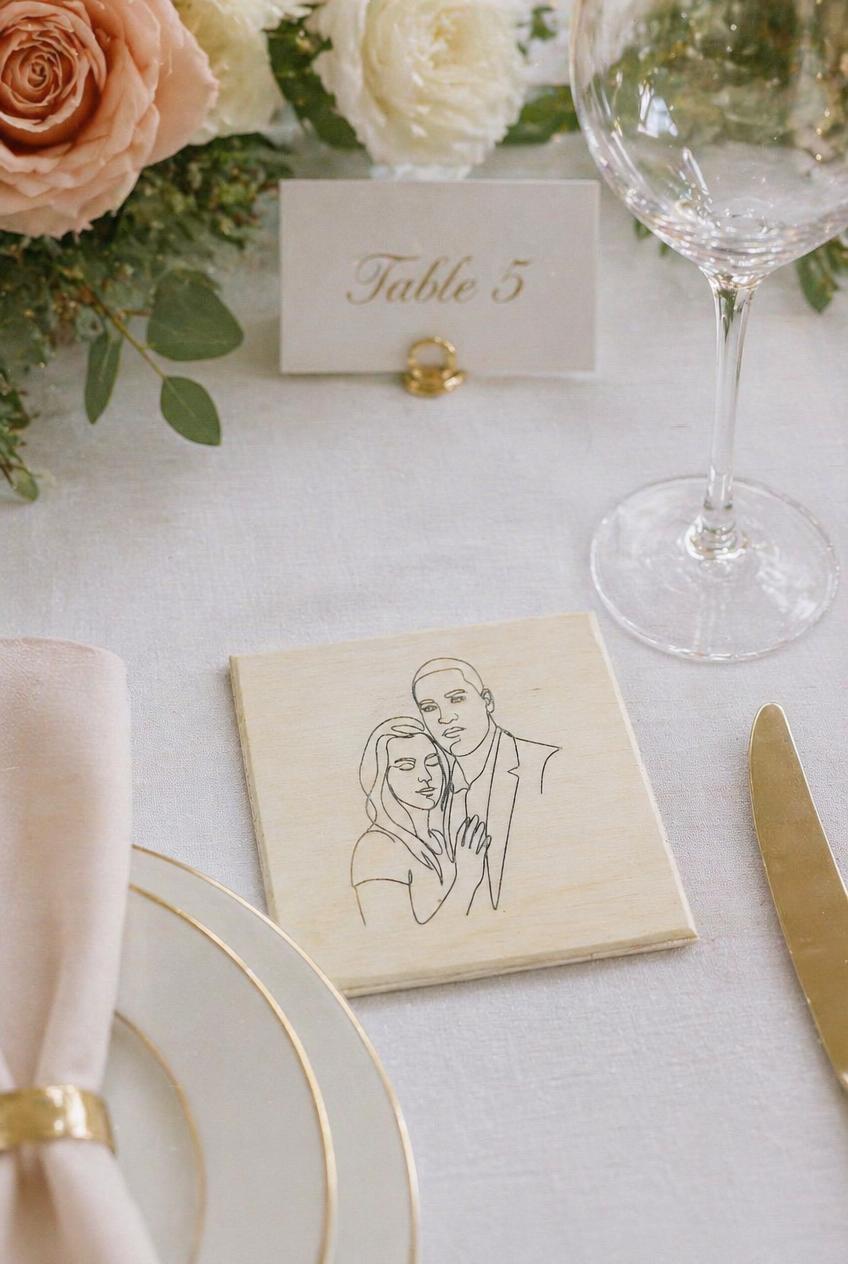 Engraved wooden coaster with line art couple portrait on an elegant wedding table